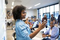African American woman at whiteboard leading a meeting.