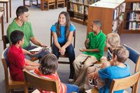 A group of middle school students gathered in chairs in a circle, talking out an issue with an adult