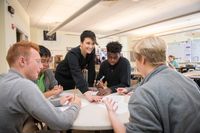 A teacher talking with a group of high school students about their writing projects