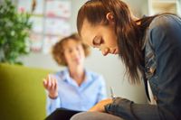 A student talks to her teacher about her frustrations in school. She looks down at the floor with sadness and uncertainty.