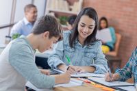 High school students sitting at a table, writing and talking