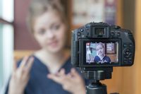A student filming herself talking on a DSLR camera