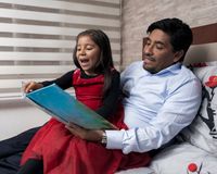 A father reading a picture book with his daughter