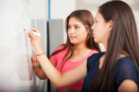 Two high school girls doing math equations on the whiteboard