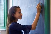 A middle school student doing algebra on a blackboard