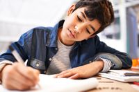 A middle school student writing in a notebook in English class
