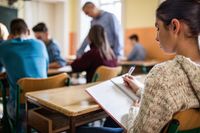 A high school student writing in a journal in class
