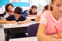 A classroom full of diverse students writing at their desks