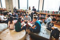 A class of students works in groups together in the library
