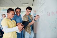 A teacher working with two students at the whiteboard