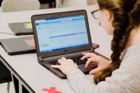 A student works on a coding project on her laptop in a classroom