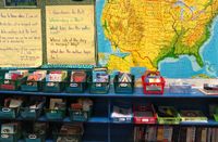 A shelf full of bins of books with a map of the United States behind it