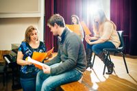 A group of high school students rehearse a scene from a play in a school auditorium