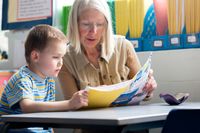 A teacher going through an elementary student's work folder with the student