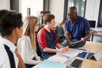 Teacher helping a group of three students in a classroom