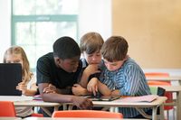 Three students in a group, looking at a tablet computer together