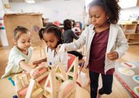 A group of young children building a house out of blocks together in a classroom