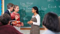 A teacher helping two Spanish language learners speak with each other in class