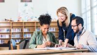 Three teachers looking at student work in the school library