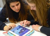 Two female high school students working together on a tablet