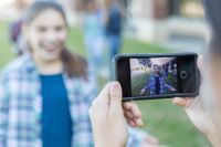 Photograph of a student recording another student with a smart phone.