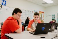 Two high school students working on a laptop together