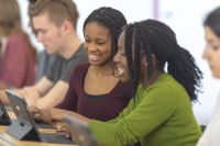 Two female high school students working together on a tablet