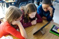 Three middle school students working on a tablet together
