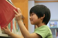 Elementary school student putting a book away on a shelf