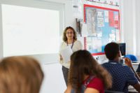 Teacher instructing students while standing in front of a smart board