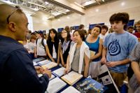 Students and parents listen to a college recruiter at a college fair
