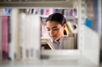 Teacher pulling a book off the bookshelf in a library