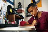 Teenager writing at his desk in his bedroom