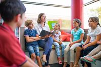 Teacher reading to seated elementary school students in a library