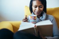 Woman sitting on a couch reading a book