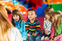 Preschool students sitting on the floor listening to their teacher