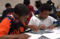 Two students using a calculator to complete math problems