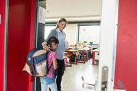 Teacher welcoming new student entering her classroom