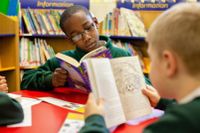 Two elementary school students sitting down and reading books