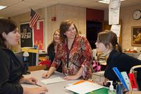 high school teacher speaks with students during a lesson