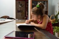 Young girl working on homework at her kitchen table
