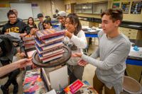 high school students stack books in a physics class
