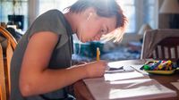 Teenager writing at her kitchen table