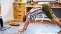 Young boy does yoga virtual class with laptop at home