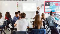 Teacher using whiteboard to teach high school class.