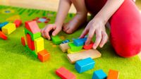 Child plays with wooden blocks on floor