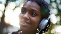 Black teen with headphones on while outside