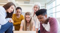 High school teacher and students work together in small group.