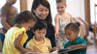 Teacher reading a book to a small group of preschool students
