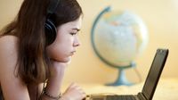 Pre-teen girl looks at laptop screen with a globe in background.